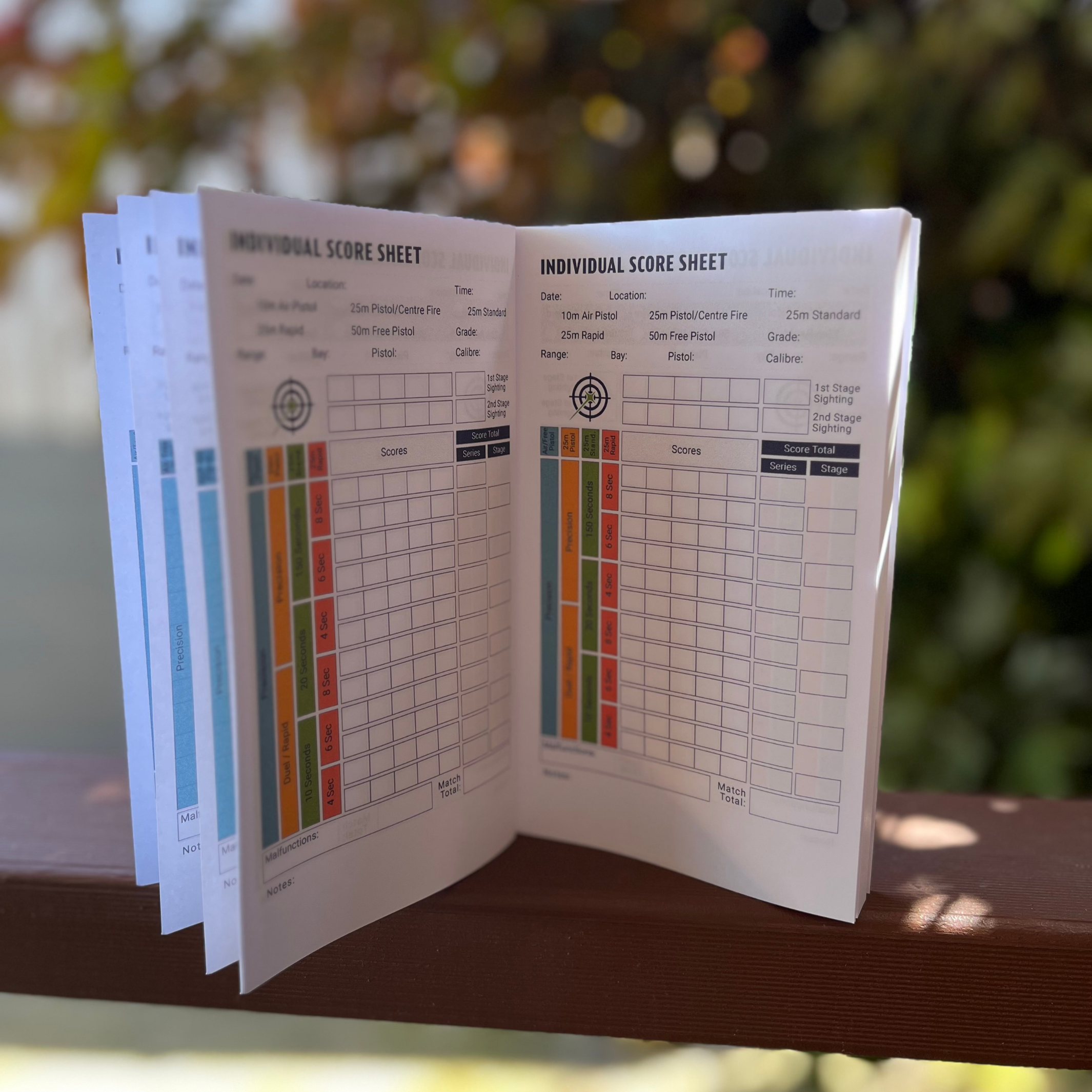 Open individual score sheet with colorful columns on a wooden surface with a blurred green background